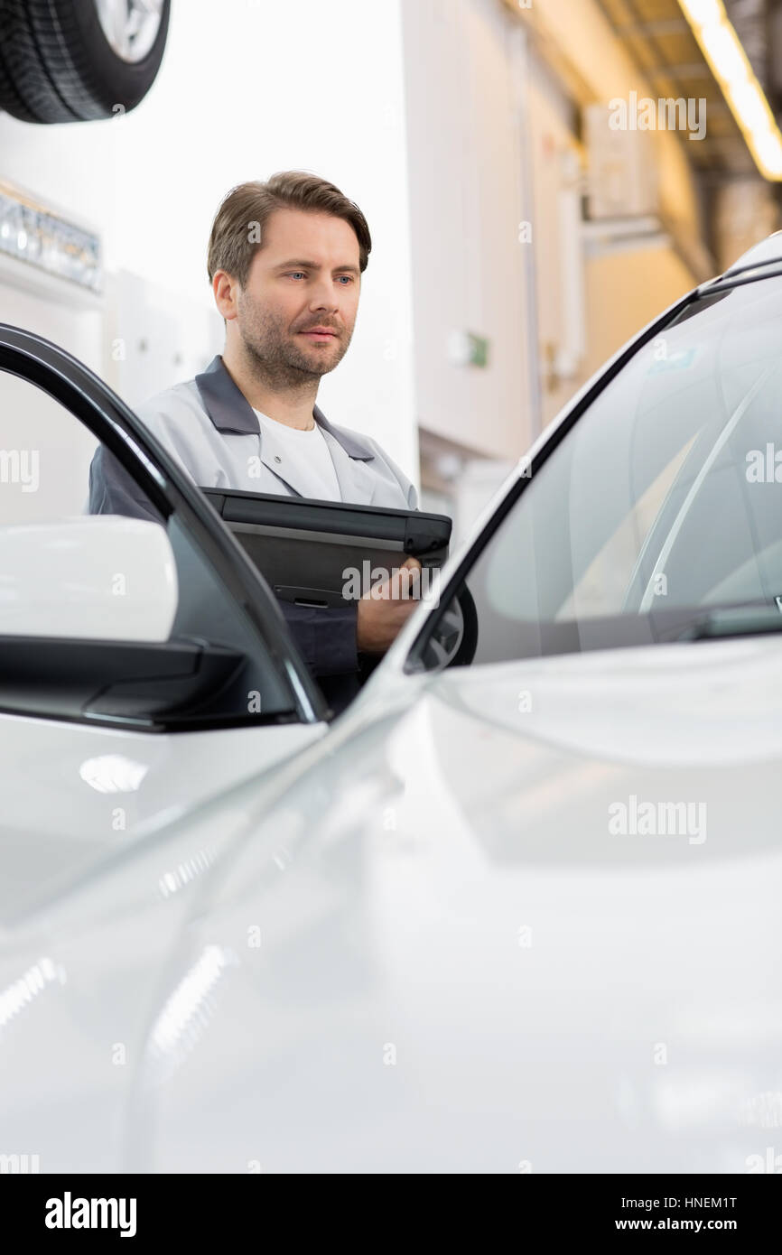 Ingénieur Maintenance holding tablet PC lors de l'examen de voiture dans l'atelier de réparation Banque D'Images