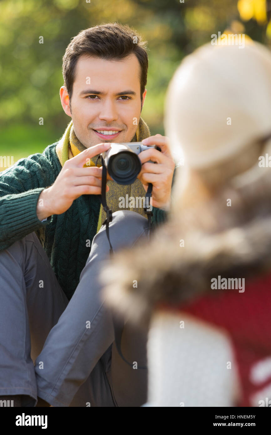Smiling young man photographing woman in park Banque D'Images