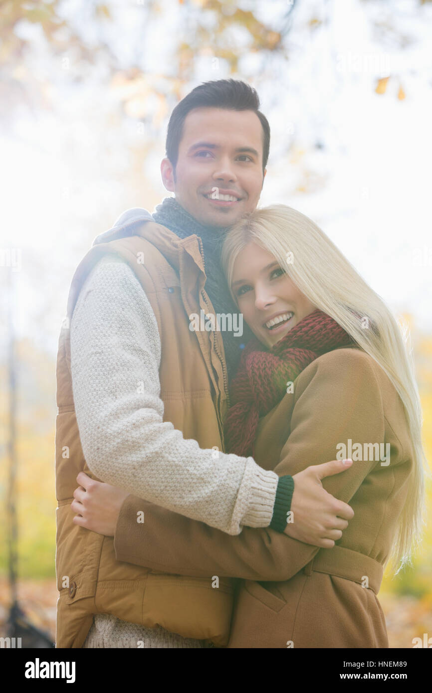 Heureux couple hugging in vestes en park Banque D'Images