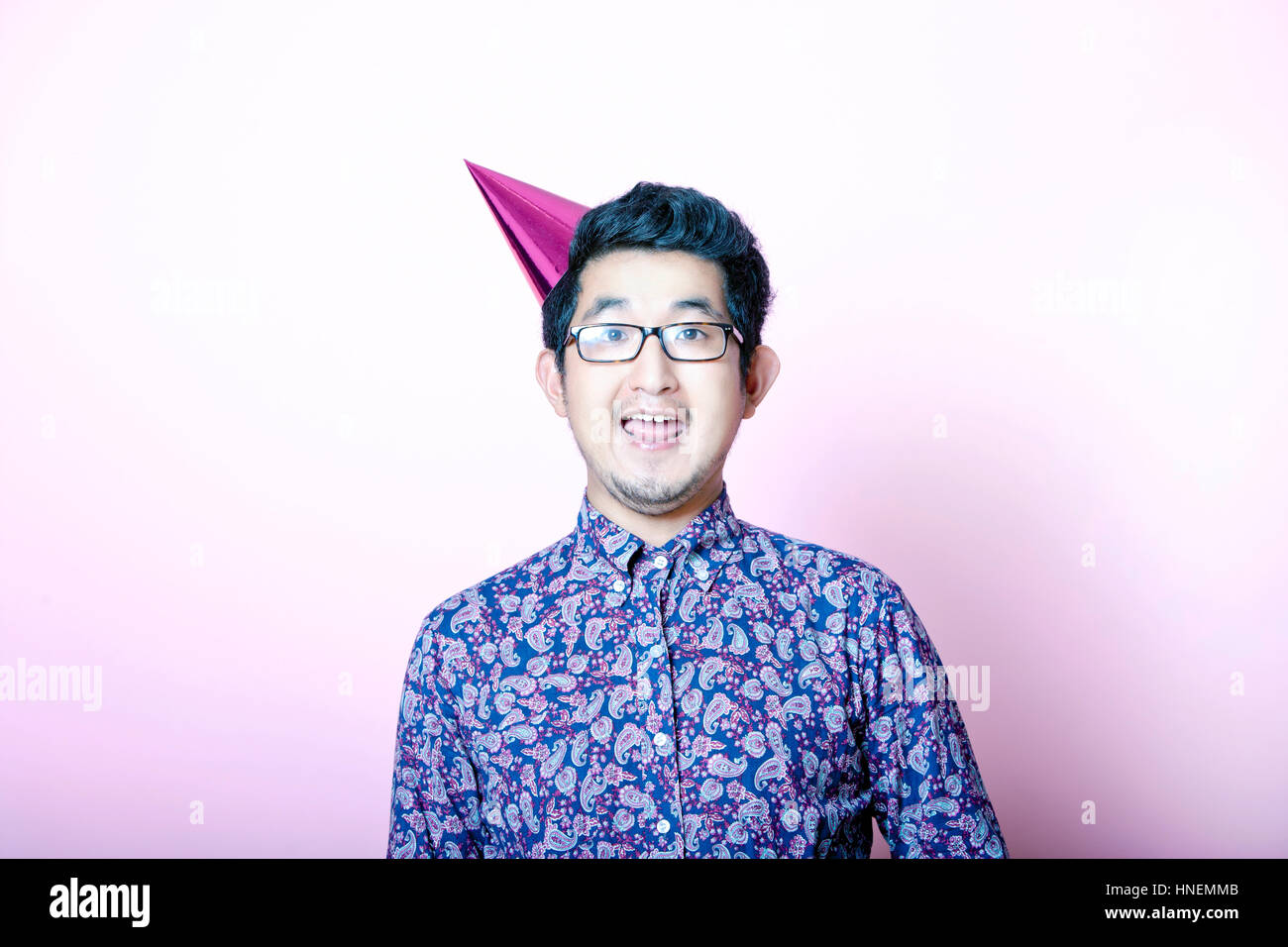 Young Geeky Asian Man wearing party hat Banque D'Images
