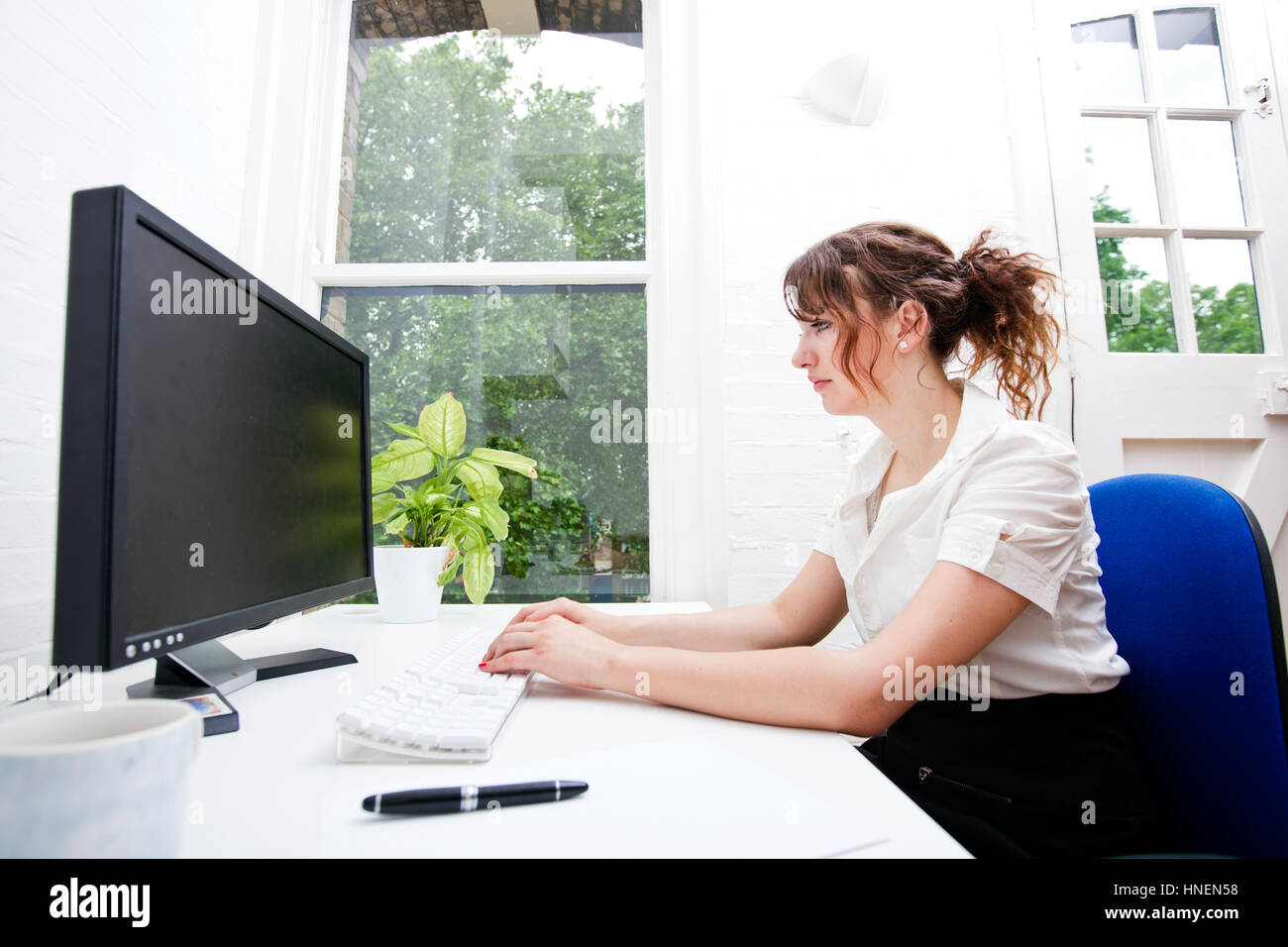 Vue latérale du young businesswoman using computer at desk Banque D'Images