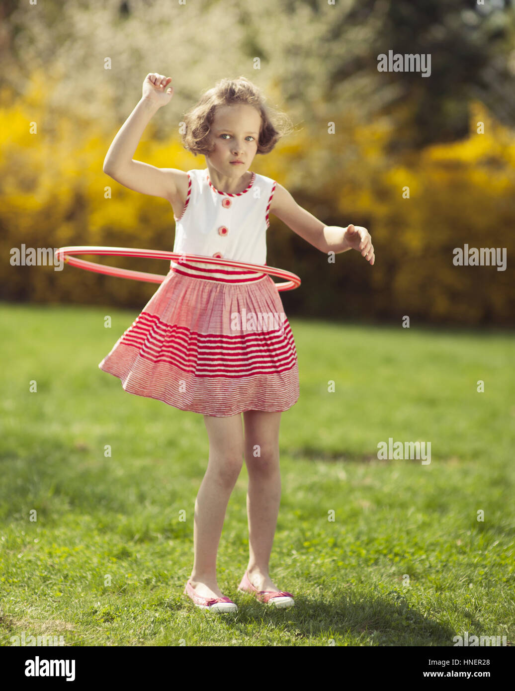 Jeune fille à l'aide de hula hoop dans un parc Banque D'Images