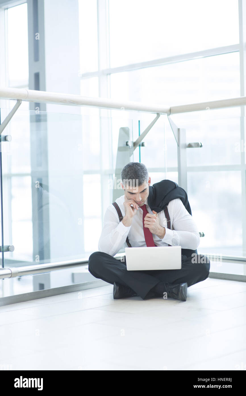 Businessman sitting on floor using laptop Banque D'Images