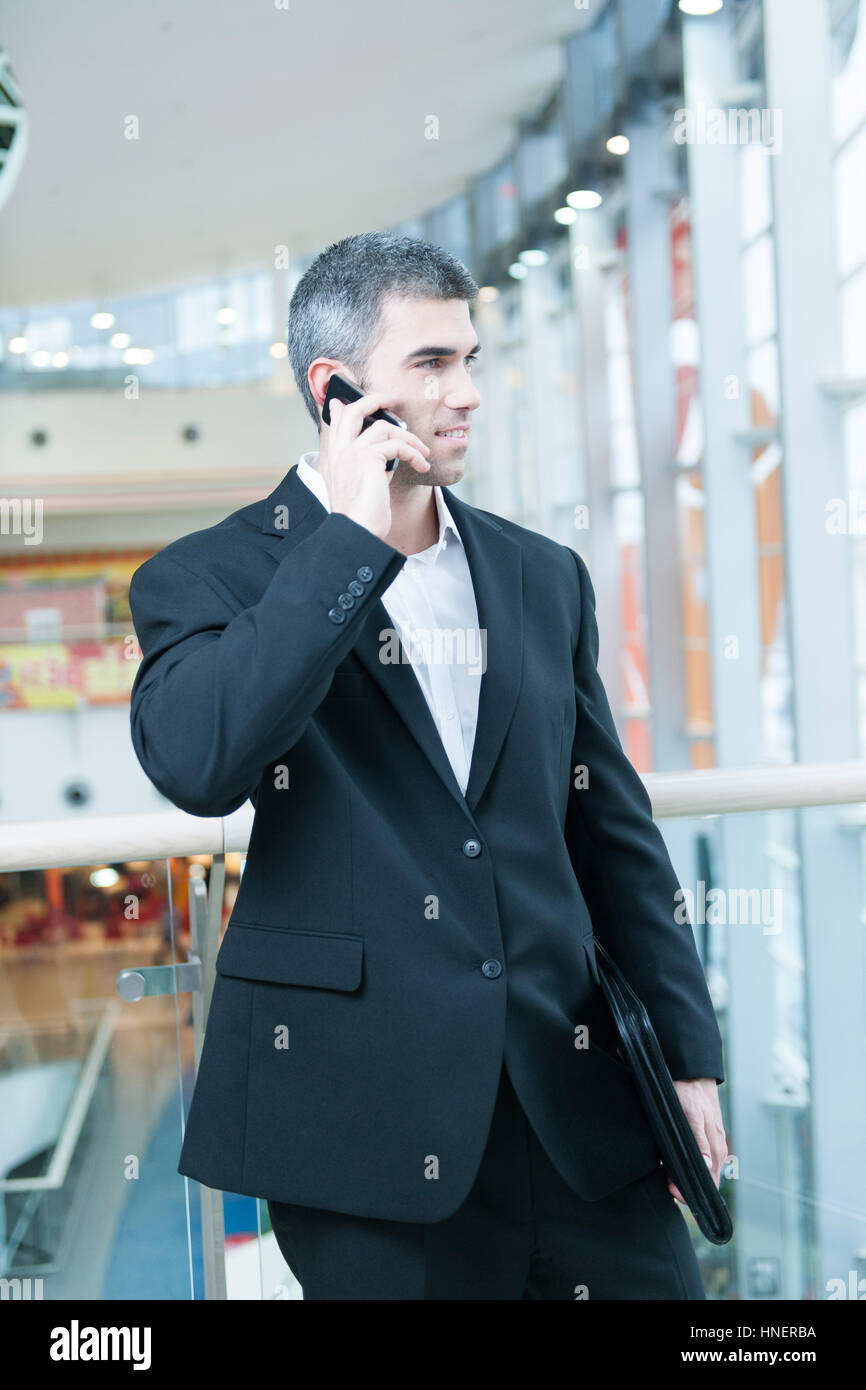 Businessman walking and talking on mobile phone Banque D'Images