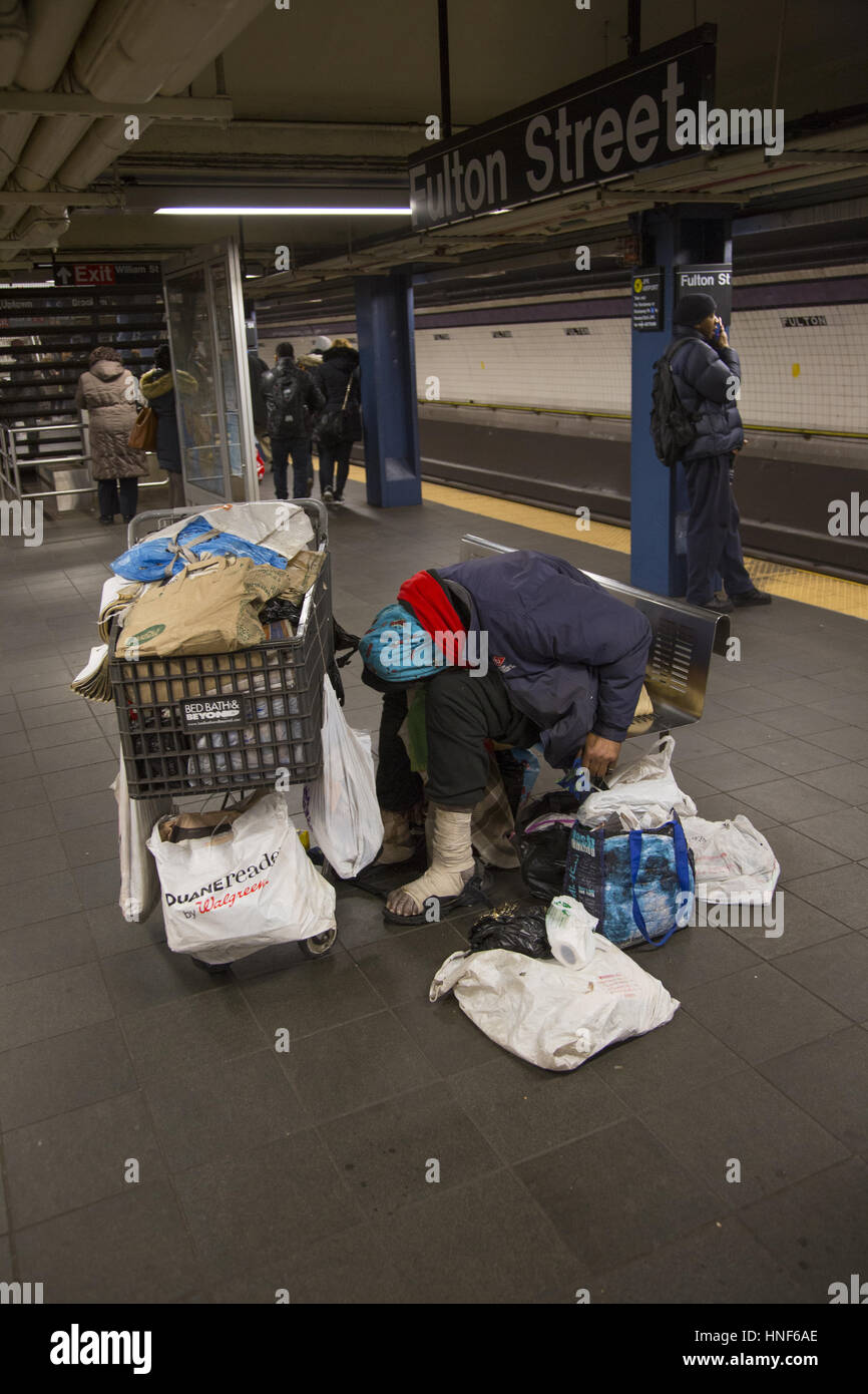 Un malade mental, personne sans-abri dort sur la plate-forme du train avec ses possessions avec lui à Fulton Street dans le centre-ville de Manhattan. Banque D'Images