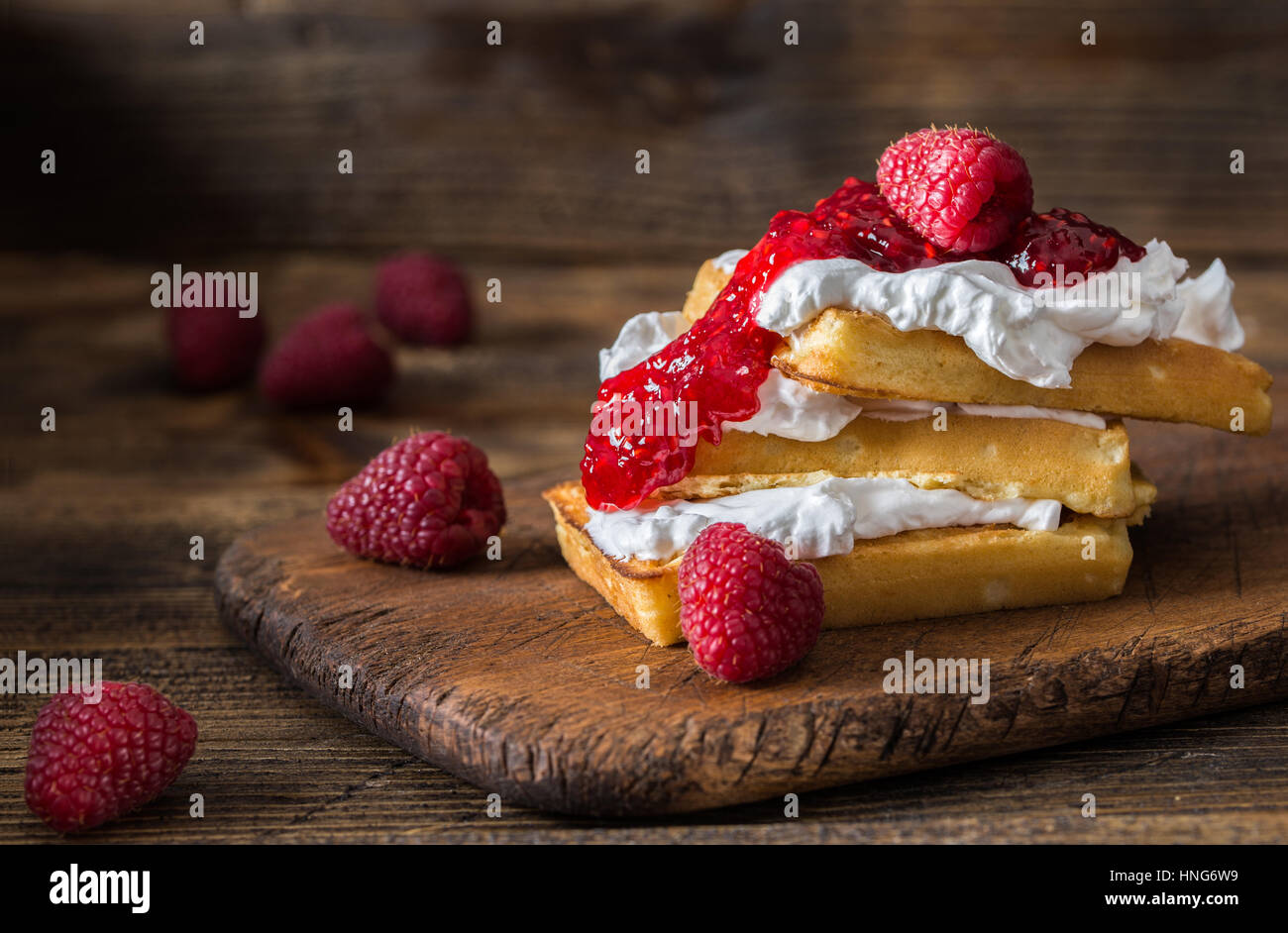 Gaufres Belges avec les framboises et la crème double sur la table rustique. Banque D'Images