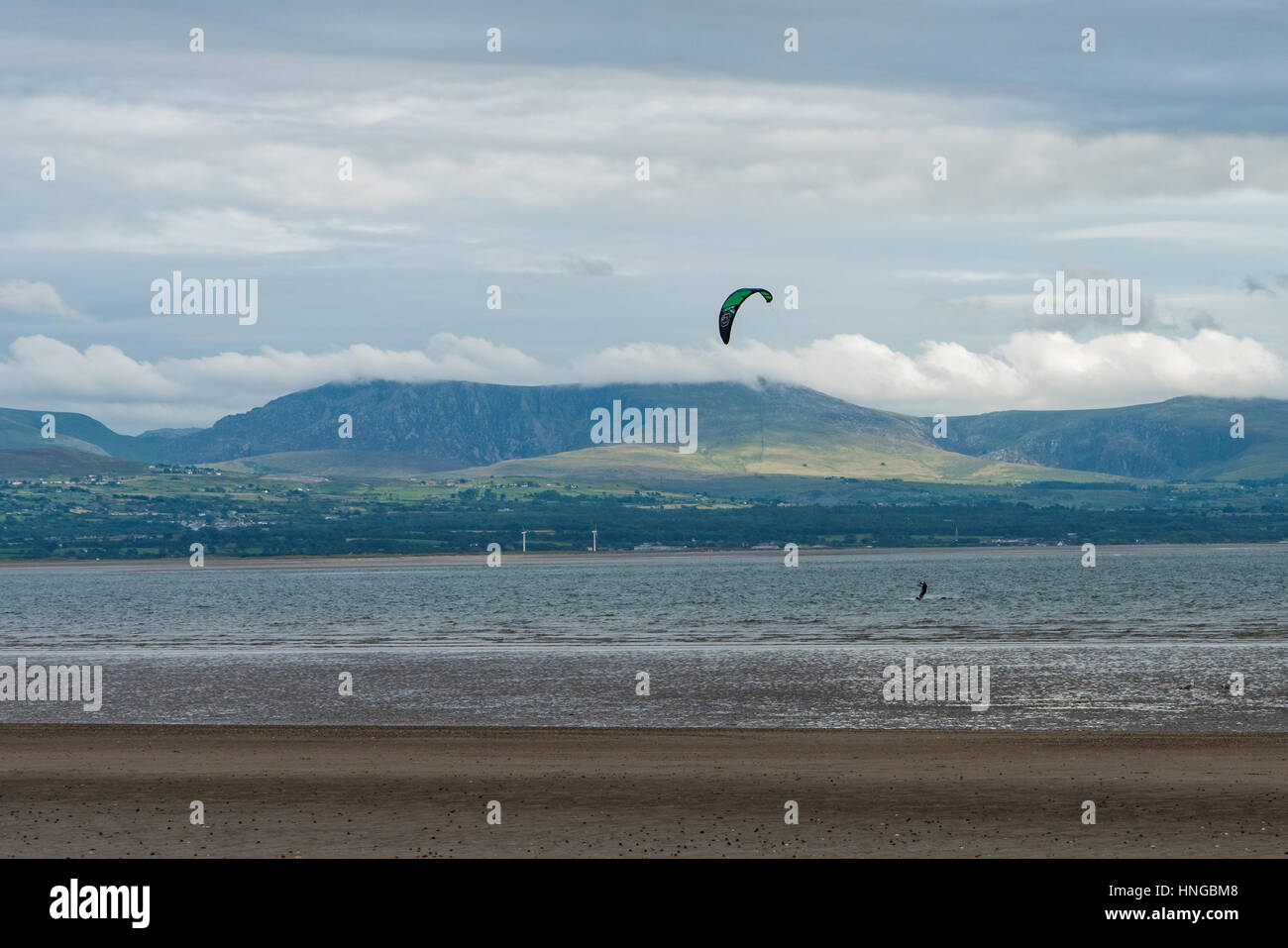 Un kite surfer off Plage Newborough Snowdonia avec en arrière-plan Banque D'Images