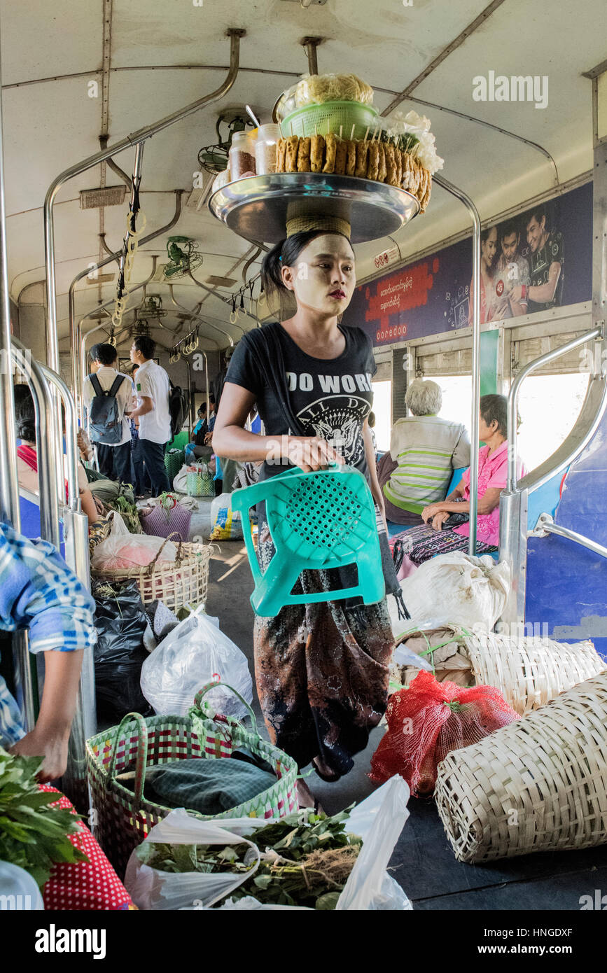 Femme birmane vendant de la nourriture dans un train avec sa production en équilibre sur sa tête quand elle marche grâce à un transport bondé Banque D'Images