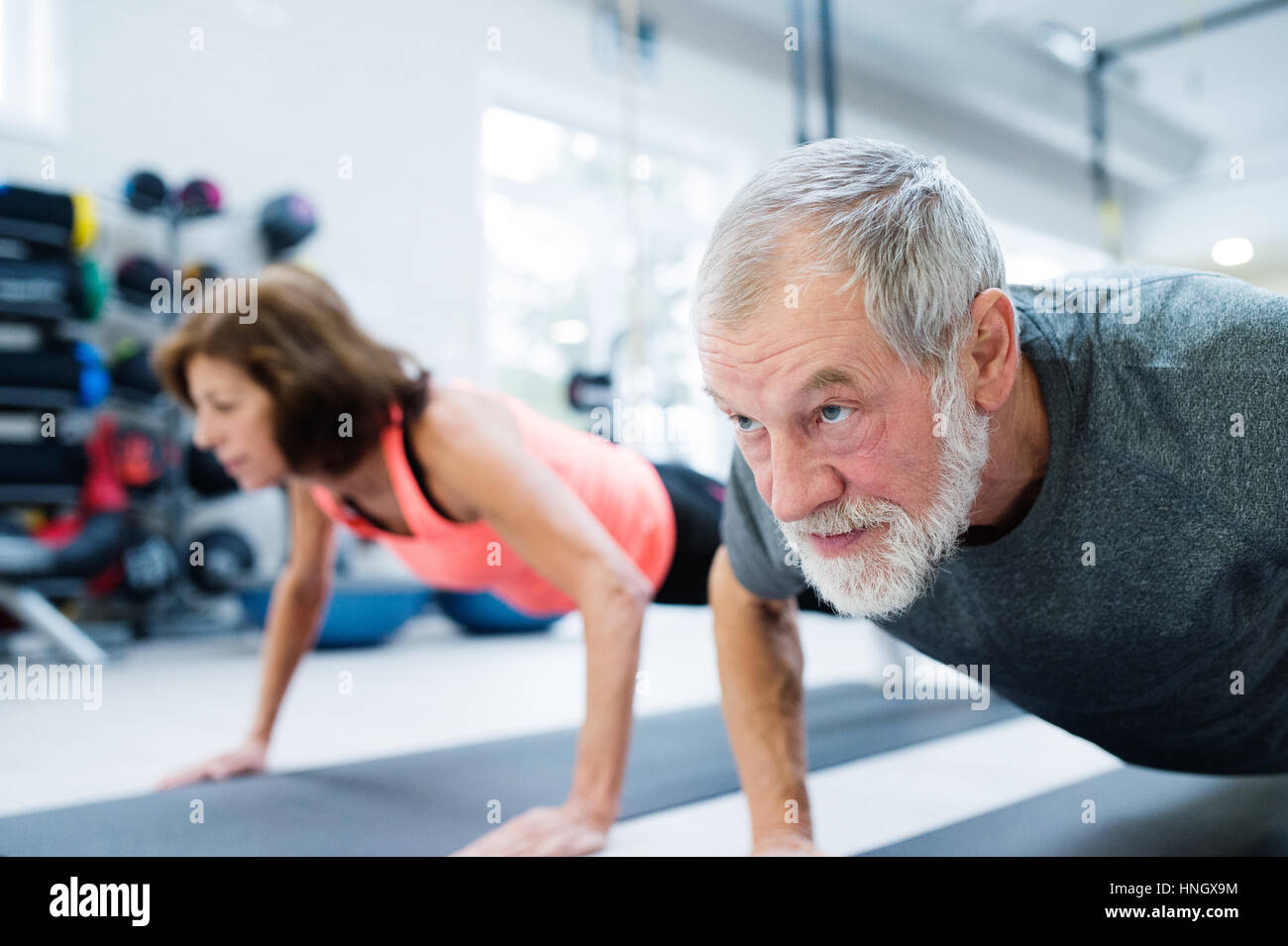 Couple dans une salle de sport de l'exercice, faisant pousser ups Banque D'Images