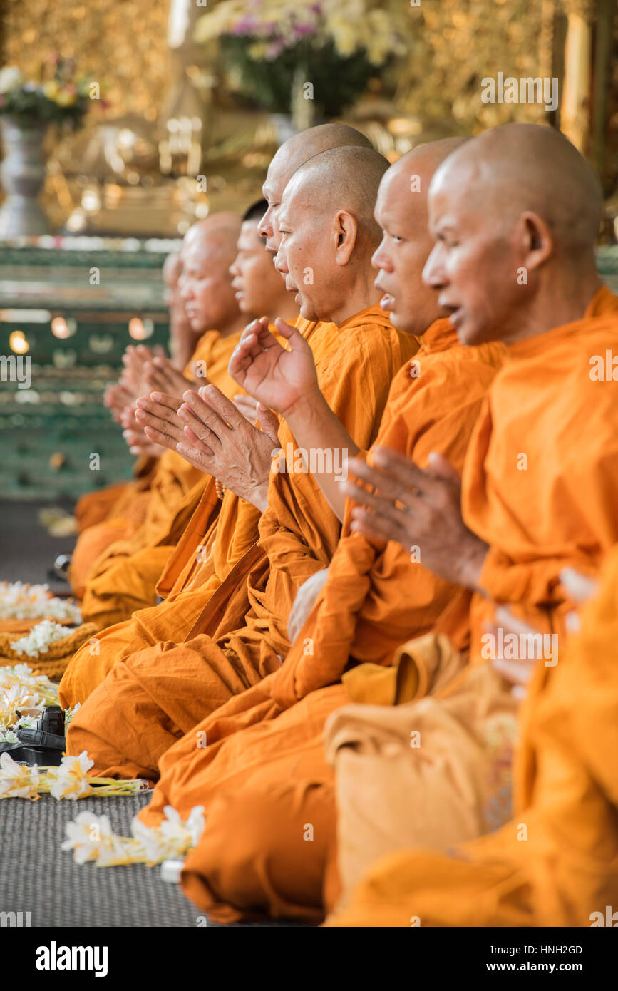Les moines bouddhistes en robe orange montrent une grande concentration de prier dans un temple assis sur le sol en position demi-lotus Banque D'Images