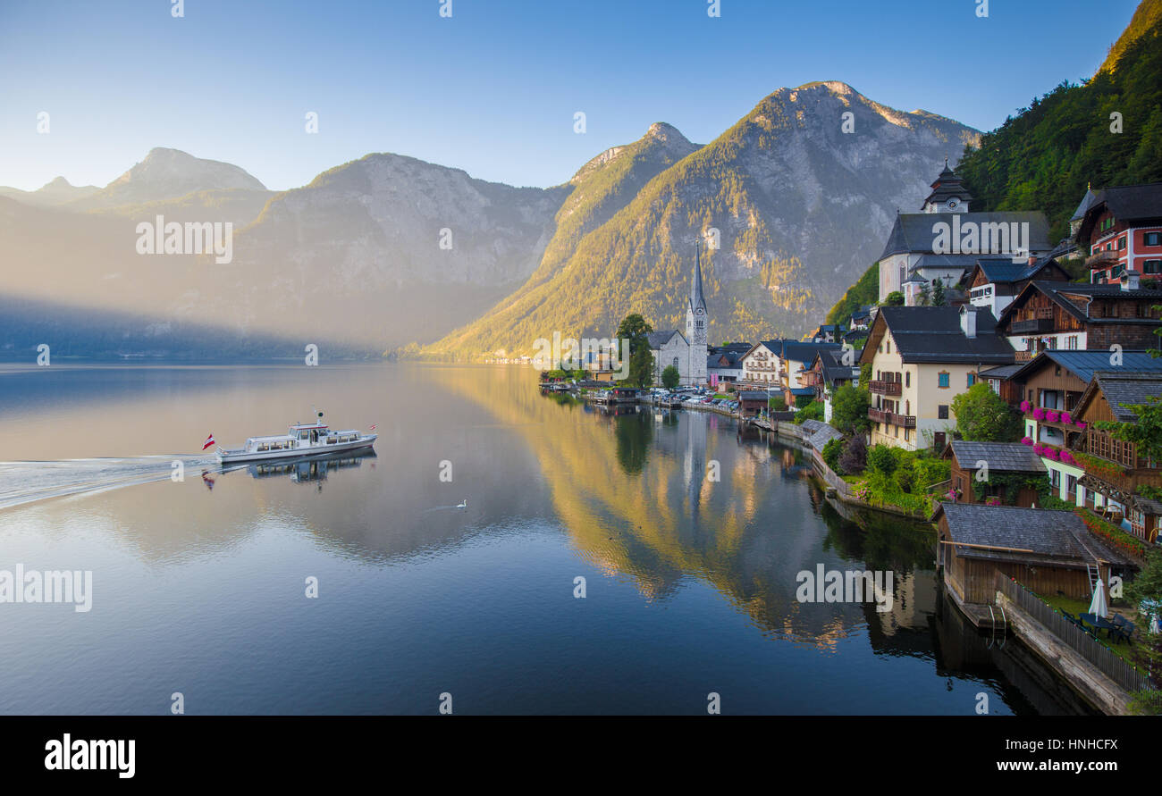 Classic vue panoramique de célèbre ville au bord du lac de Hallstatt dans les Alpes avec des passagers à bord d'un navire traditionnel dans la belle lumière du matin à l'aube, Autriche Banque D'Images