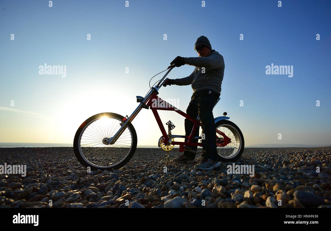 Ingelmunster, East Sussex, UK. Feb 13, 2017. Météo britannique. Charlie bénéficiant sous le soleil du soir après une belle journée ensoleillée dans le Sussex, équitation un vélo Schwinn custom cruiser. Crédit : Peter Cripps/Alamy Live News Banque D'Images