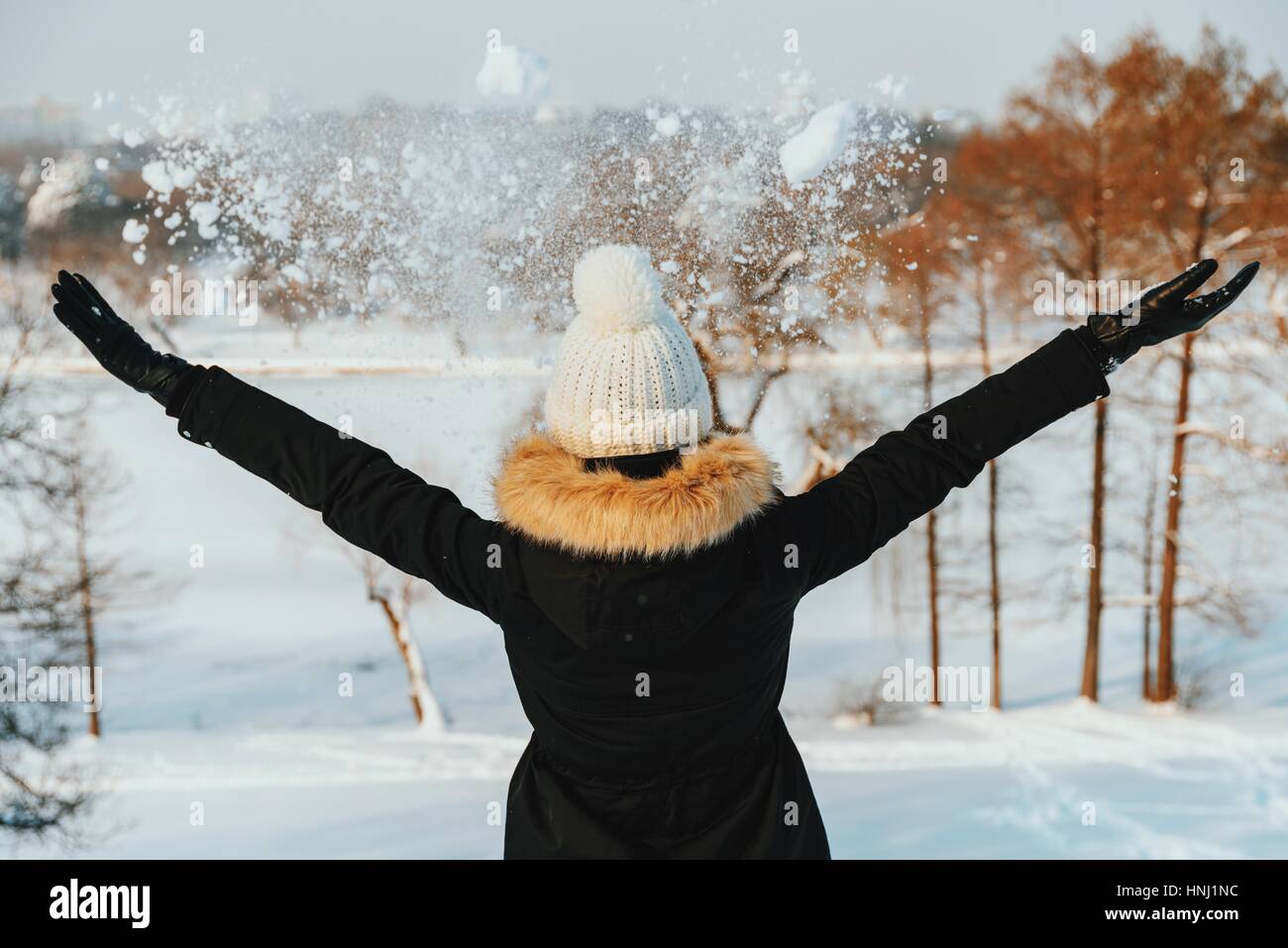 Girl Throwing Snow dans l'air pendant l'hiver Banque D'Images