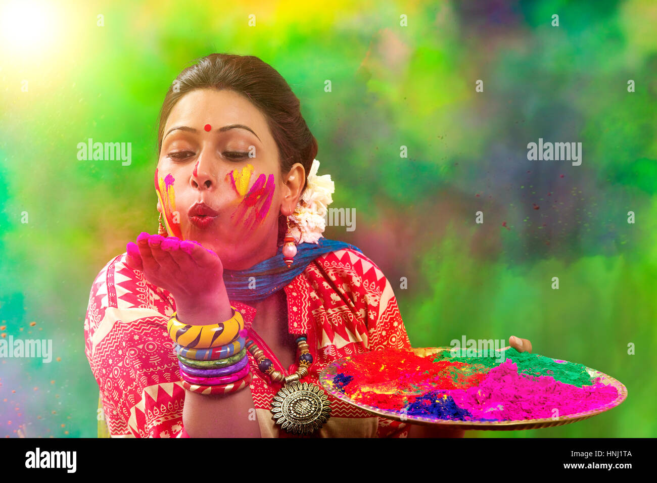 Portrait d'une femme indienne célébrant Holi en soufflant de la poudre de Holi Banque D'Images