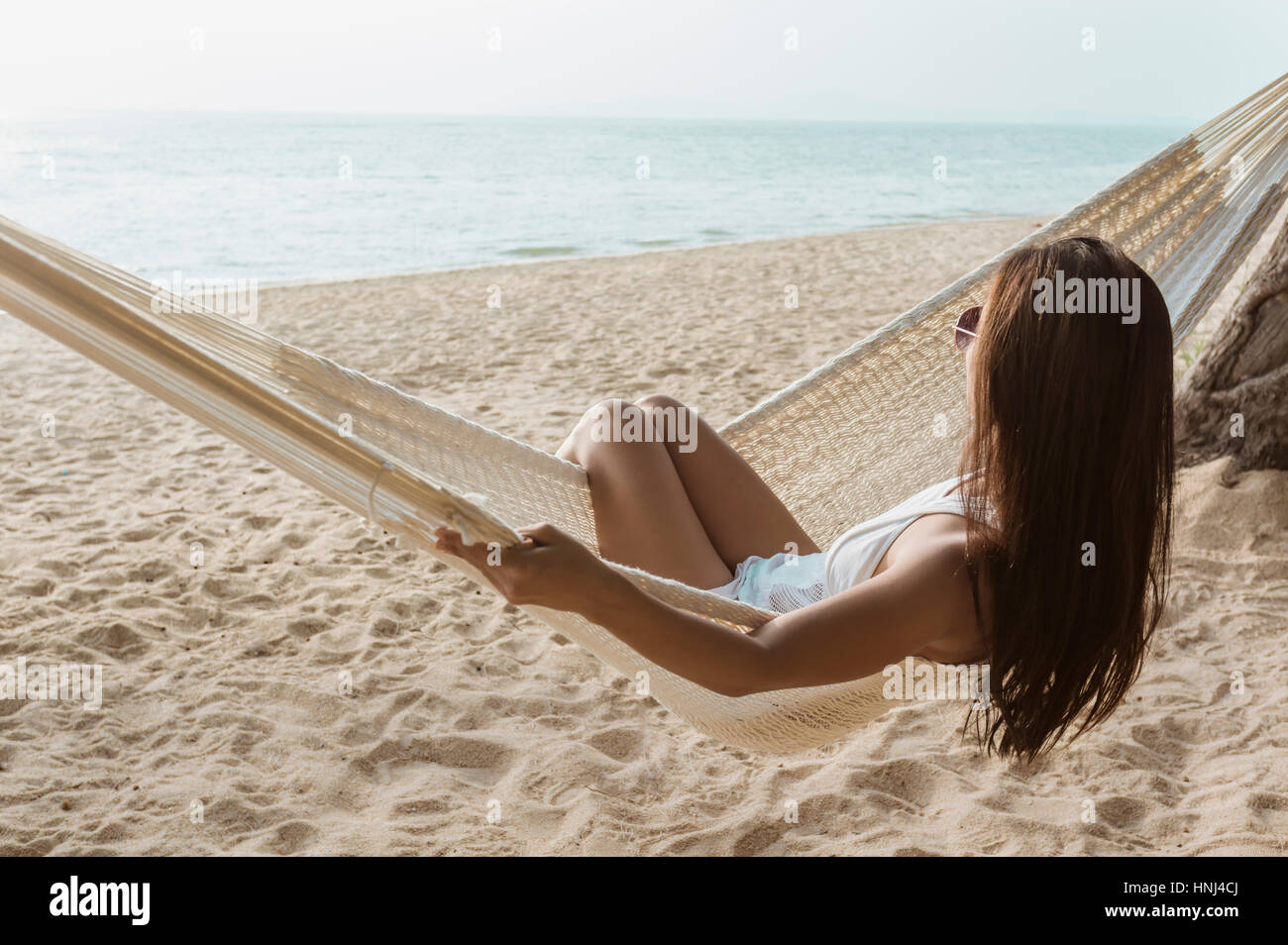 Woman relaxing on hammock at beach Banque D'Images