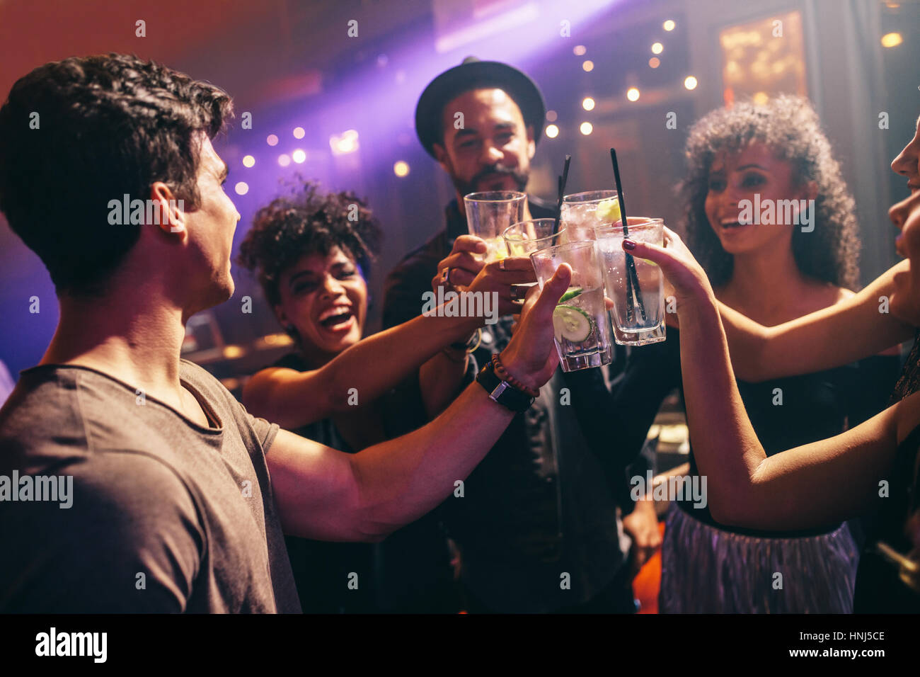 Heureux les jeunes amis en bar with cocktails. Groupe d'hommes et de femmes au célèbre discothèque avec boissons. Banque D'Images