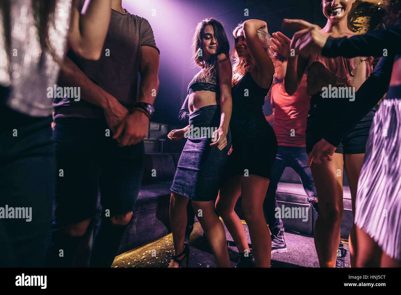Groupe de personnes dansant dans une discothèque. Jeune femme avec des amis danser dans une discothèque. Banque D'Images