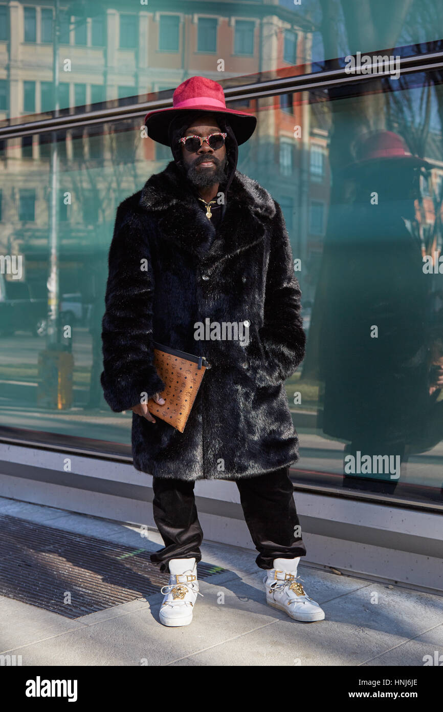 MILAN - janvier 17 : Homme avec manteau de fourrure noire, red hat et Versace baskets avant de Giorgio Armani fashion show, Milan Fashion Week street style sur Janua Banque D'Images