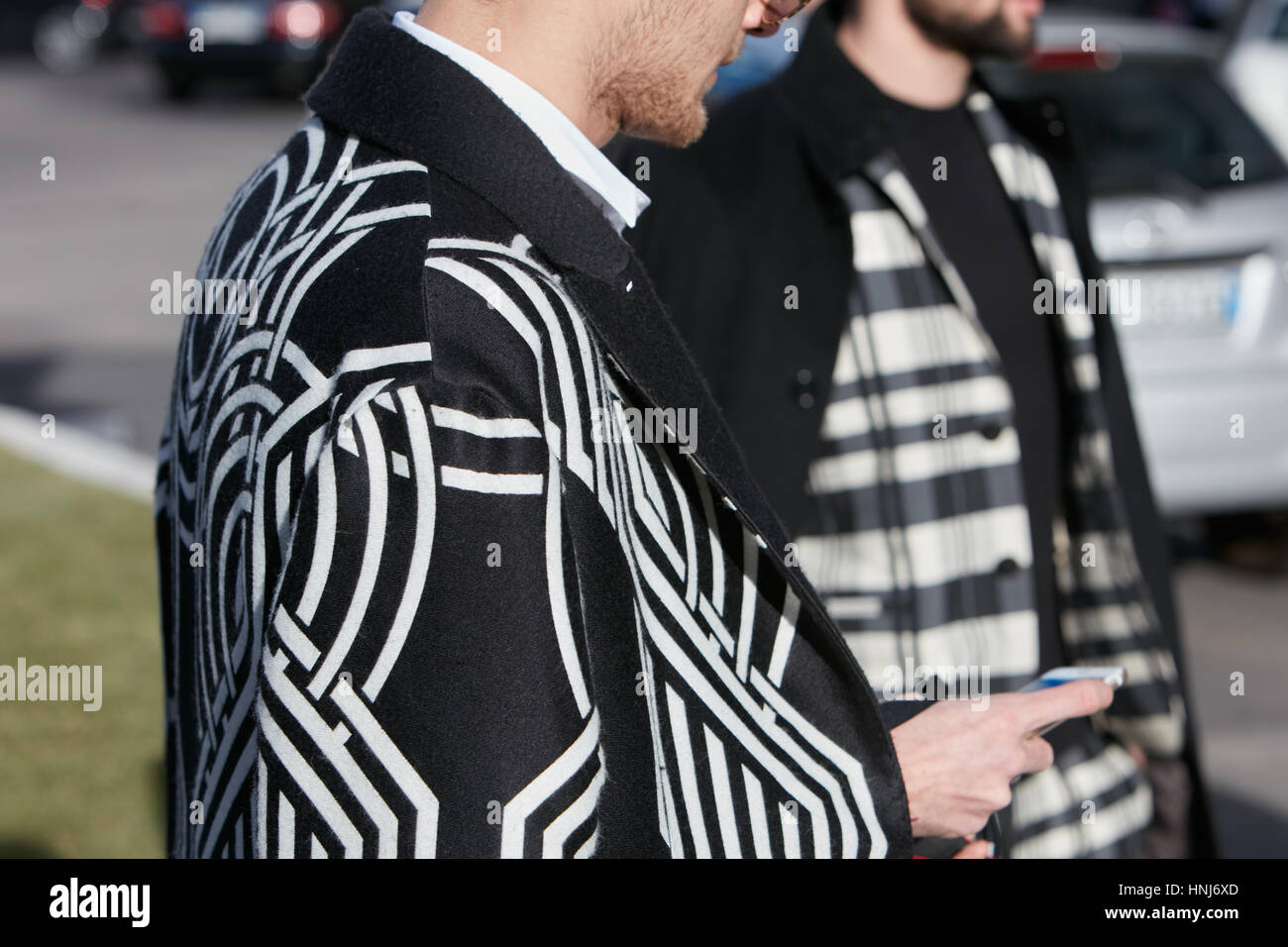 Homme avec manteau noir et blanc avec des motifs géométriques avant d'Emporio Armani fashion show, Milan Fashion Week street style sur Janvier Banque D'Images
