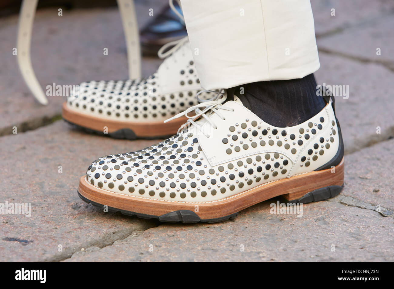 Homme avec des chaussures en cuir blanc avec clous avant de Salvatore Ferragamo fashion show, Milan Fashion Week street style le 15 janvier 2017. Banque D'Images