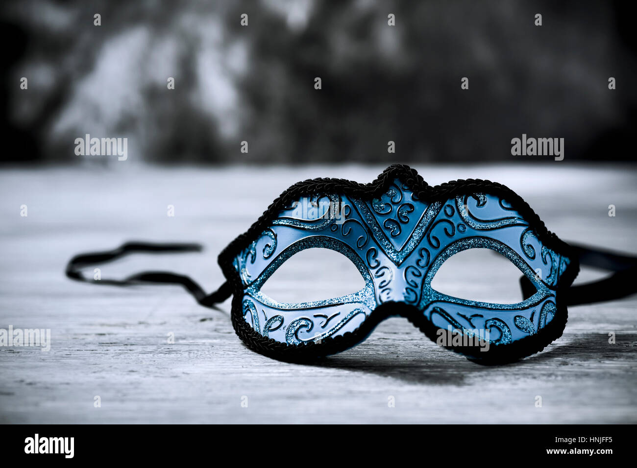 Un élégant masque carnaval bleu et noir sur une surface en bois 