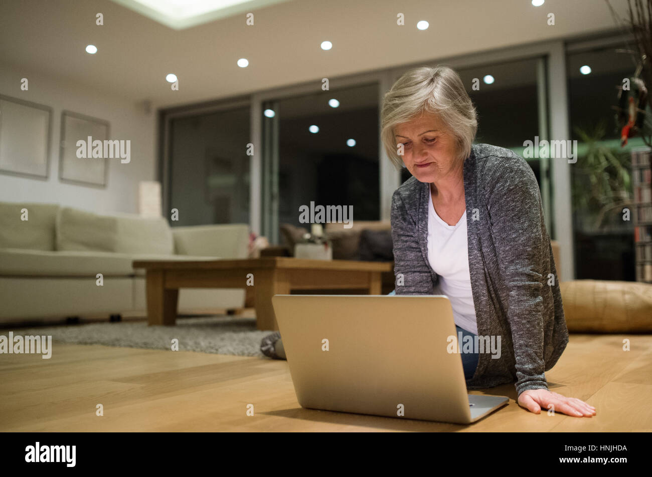 Senior woman sitting on the floor working on laptop Banque D'Images