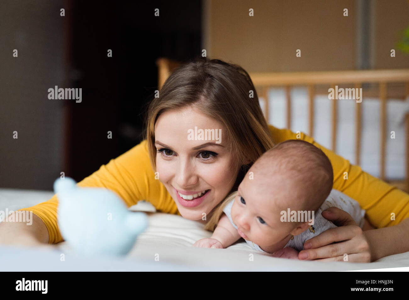 Mère avec son nouveau-né fils lying on bed Banque D'Images