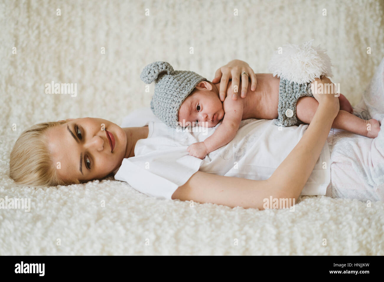 Bebe Garcon Vetu D Un Costume De Lapin Etreint Par Sa Mere Qui Est Assis Sur Son Dos Sur Un Lit Contemplant Photo Stock Alamy