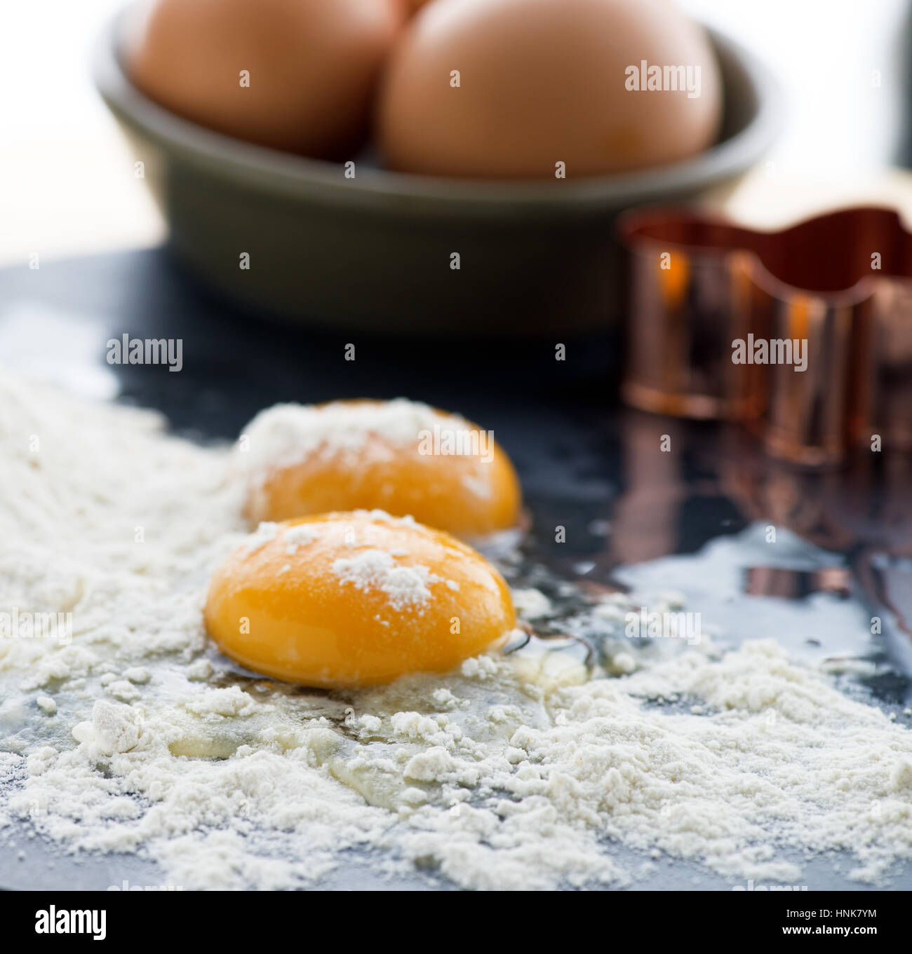 Les œufs crus l'accent sur l'œuf avec la farine et les oeufs entiers en arrière-plan, selective focus à ad copie espace tourné en un carré, formatt Banque D'Images