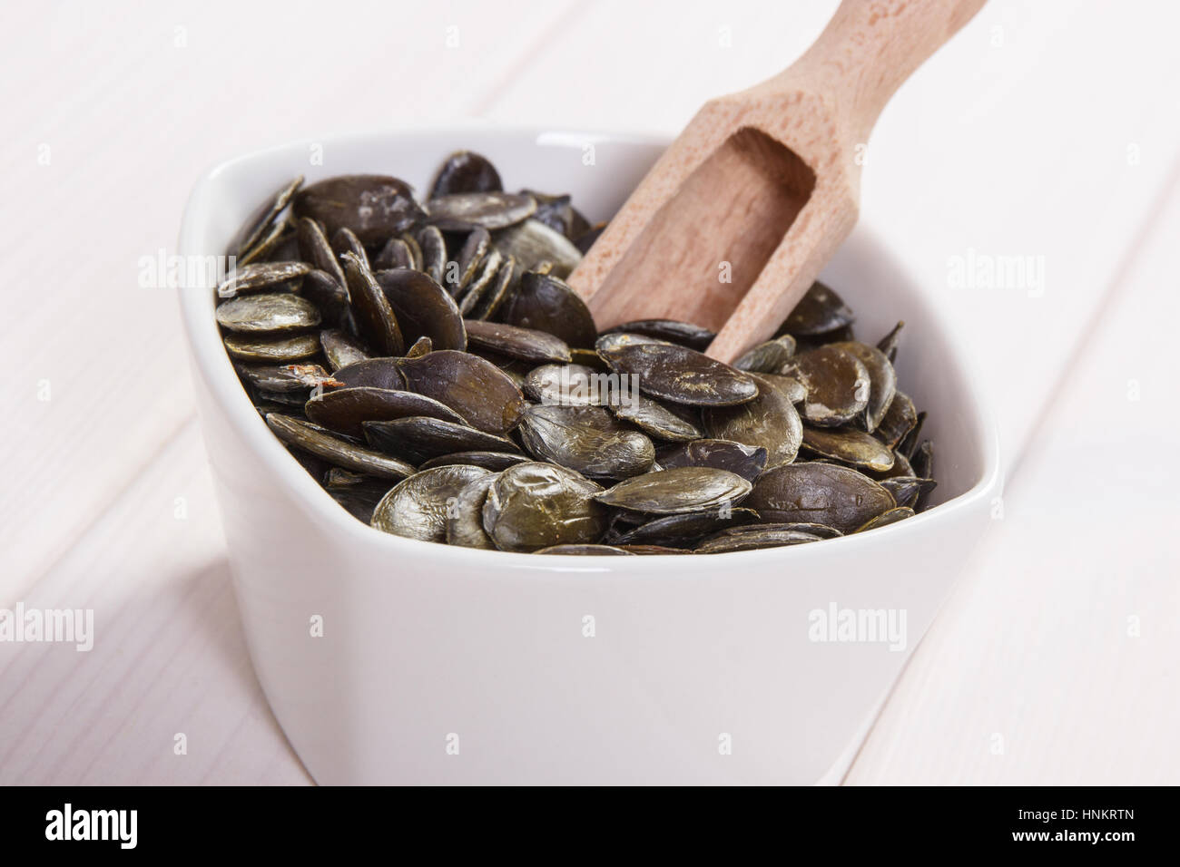 Bol blanc avec les graines de citrouille contenant du zinc et de fibres alimentaires sur les tableaux blancs, les sources naturelles de minéraux, mode de vie sain et nutrition Banque D'Images