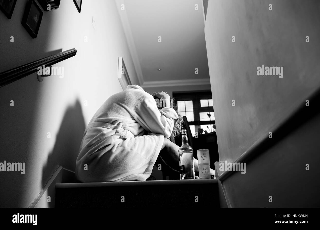 Femme assise enfoncée dans sa robe de chambre à la maison pendant la journée à boire fortement traiter eux-Photographie - posée par model Banque D'Images