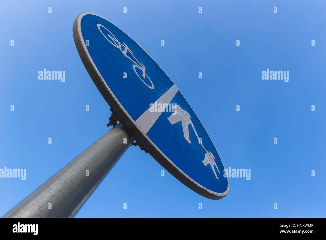 Piste cyclable obligatoire pour les piétons et les cycles (double voie ; sur la piste cyclable, sentier de gauche à droite). Panneau routier d'une faible perspective. Sur bleu ciel clair Banque D'Images