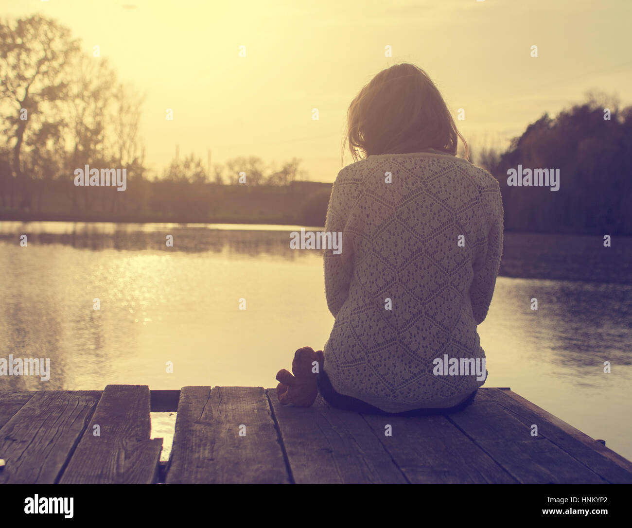 Woman relaxing on jetée en bois dans le coucher du soleil au bord du lac Banque D'Images