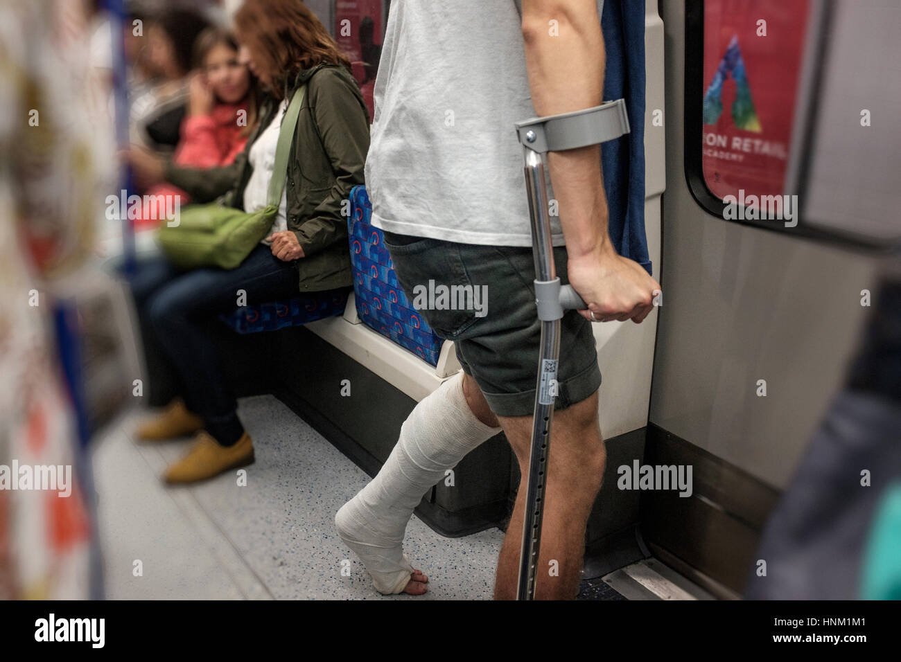 L'homme sur des béquilles avec plâtre sur les transports publics, le métro de Londres, Angleterre Banque D'Images