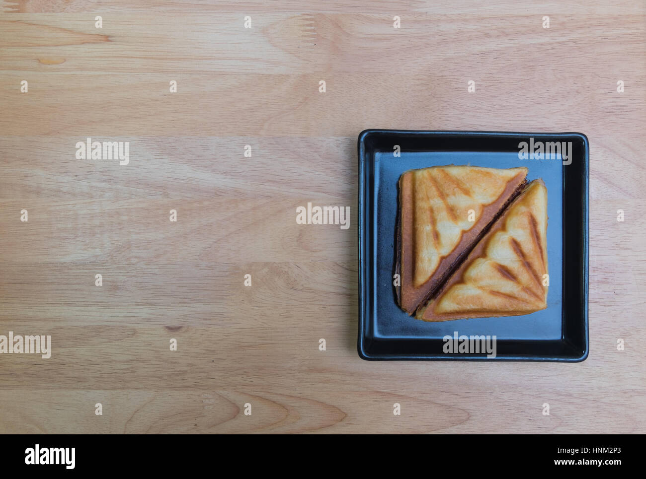 Fromage jambon toast en carré noir disque sur le contreplaqué tabe. Banque D'Images