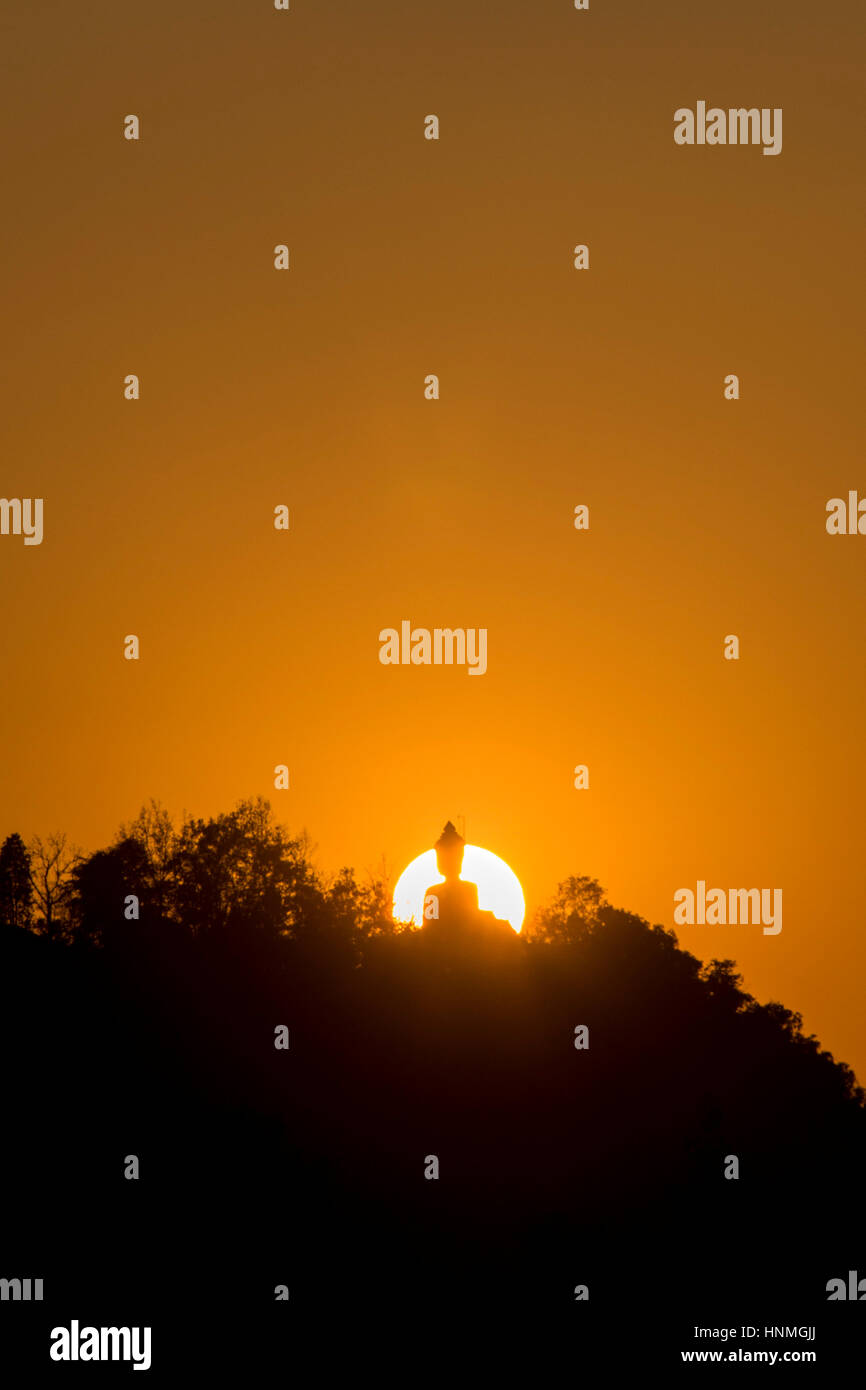 Silhouette de Bouddha monument situé sur le pic de montagne avec le soleil couchant en arrière-plan. Banque D'Images