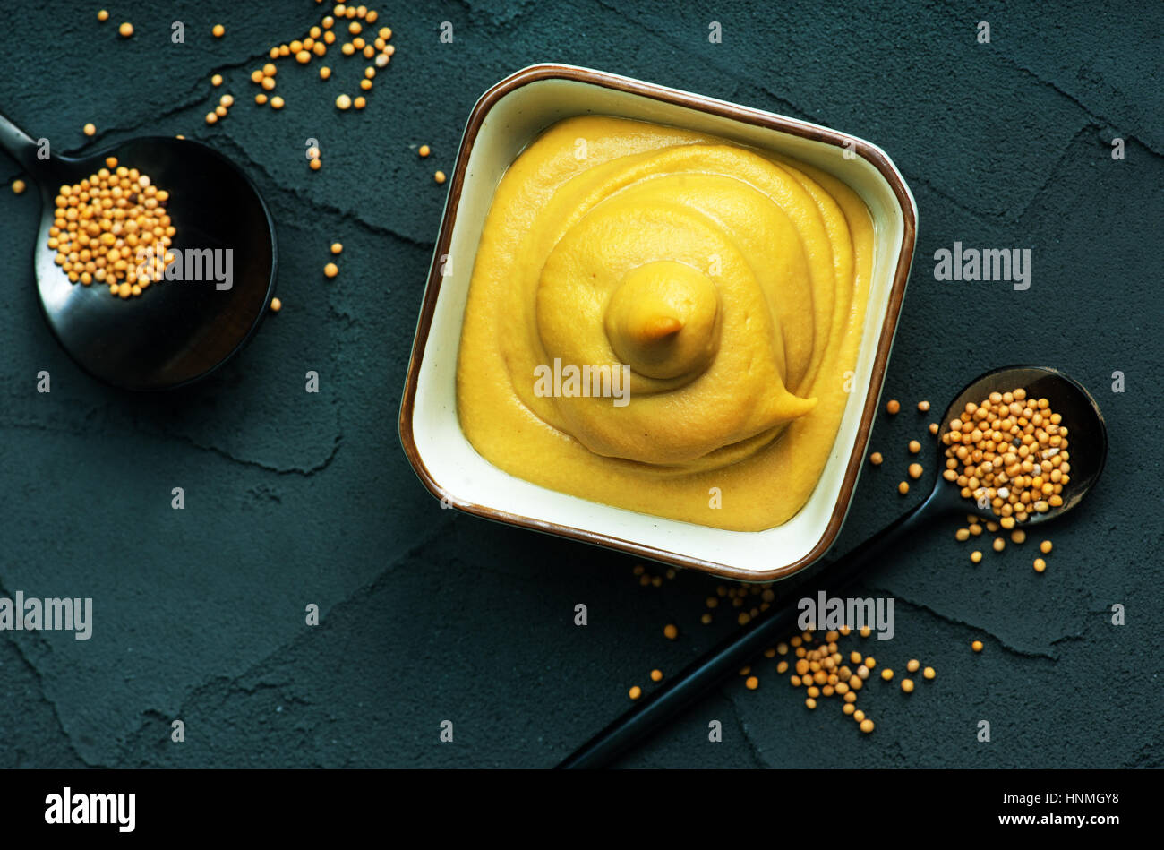 La moutarde dans un bol et sur une table Banque D'Images