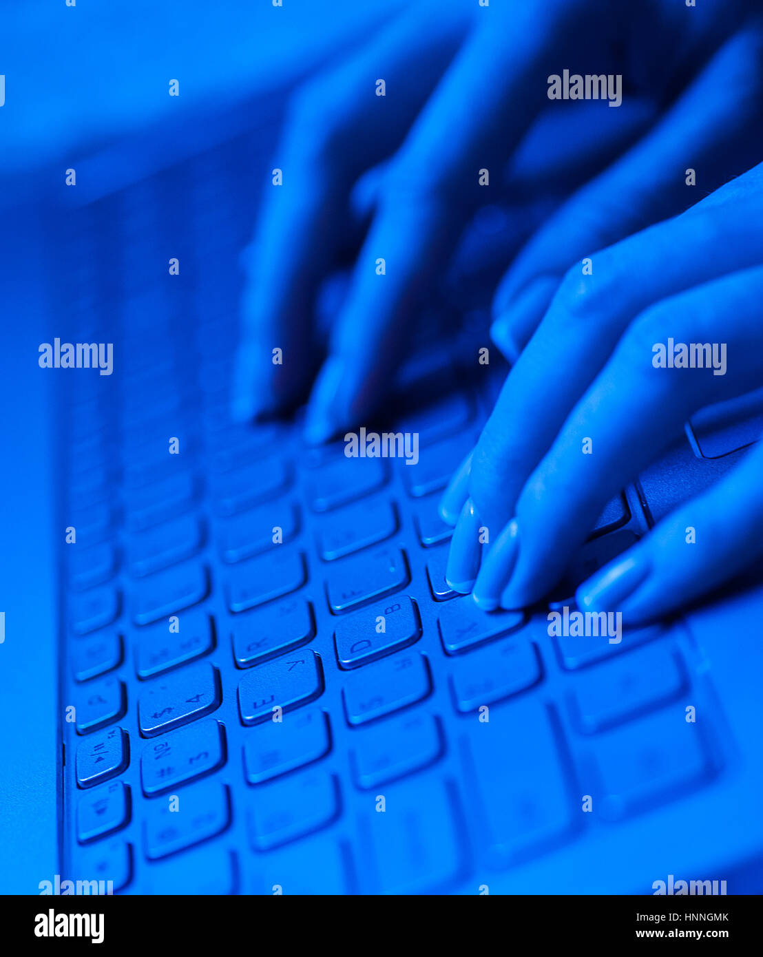 Femme doigts du clavier de l'ordinateur portable dans des tons bleus Banque D'Images