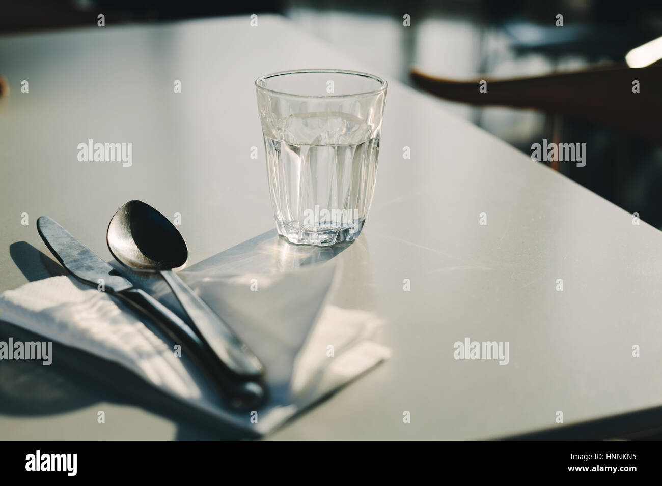 La lumière du soleil verre d'eau et des couverts sur une table Banque D'Images