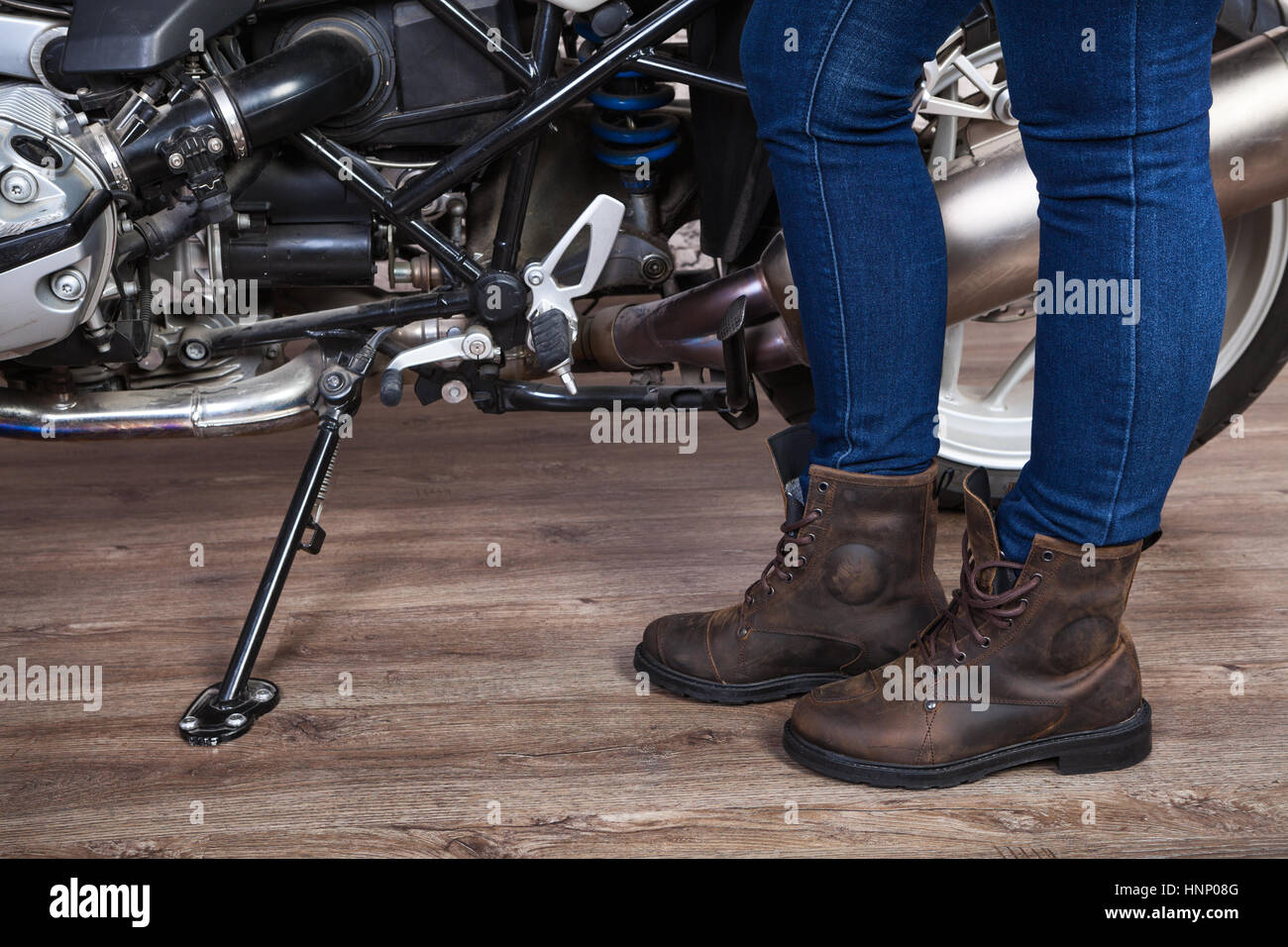 Les jambes des femmes portant des bottes de sécurité en cuir brun pour la moto sont près de moto, vue en gros Banque D'Images