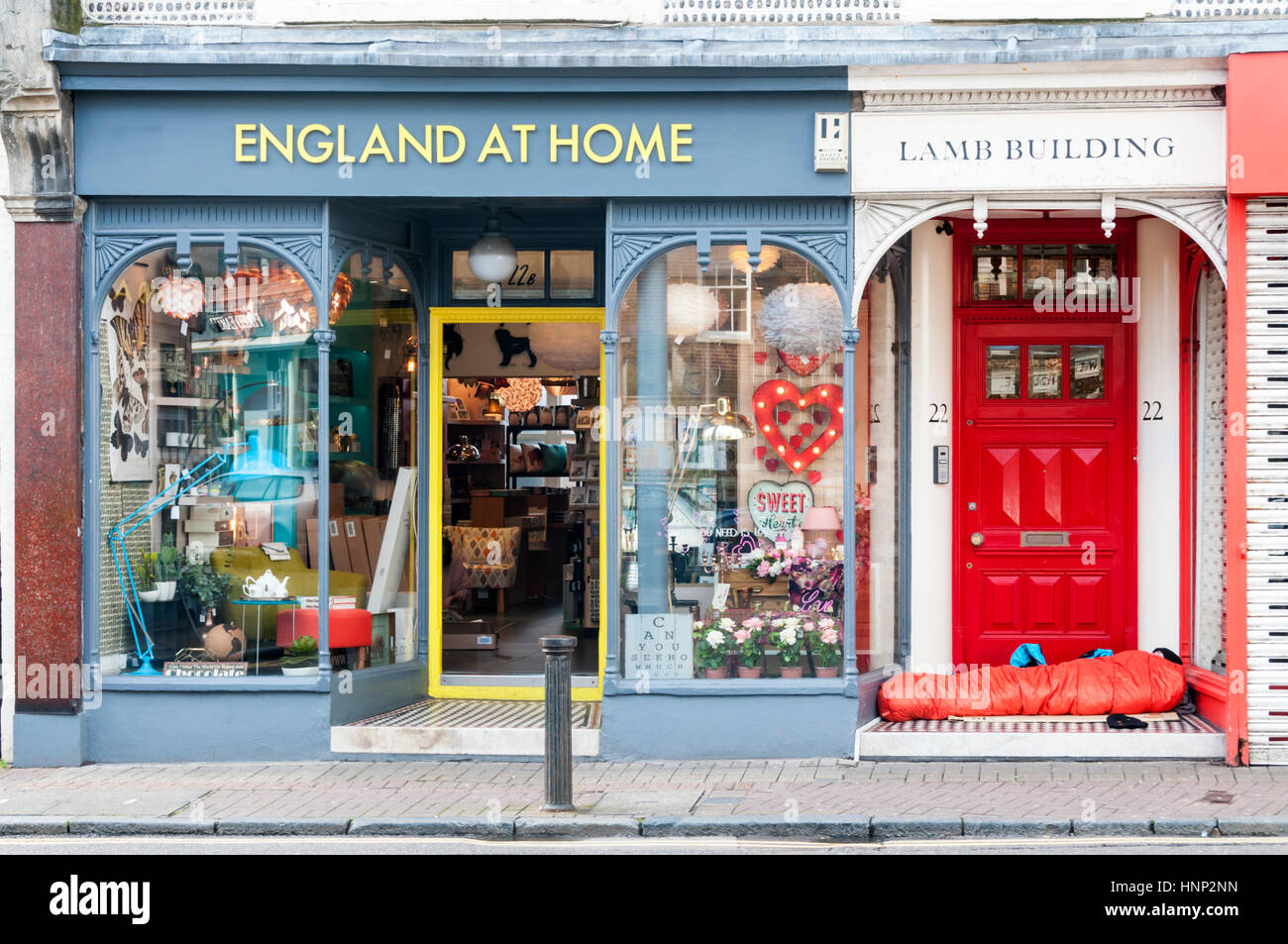 L'ironie d'un sans-abri rough sleeper à Brighton, dormant dans une porte à côté de l'Angleterre à la maison boutique Banque D'Images