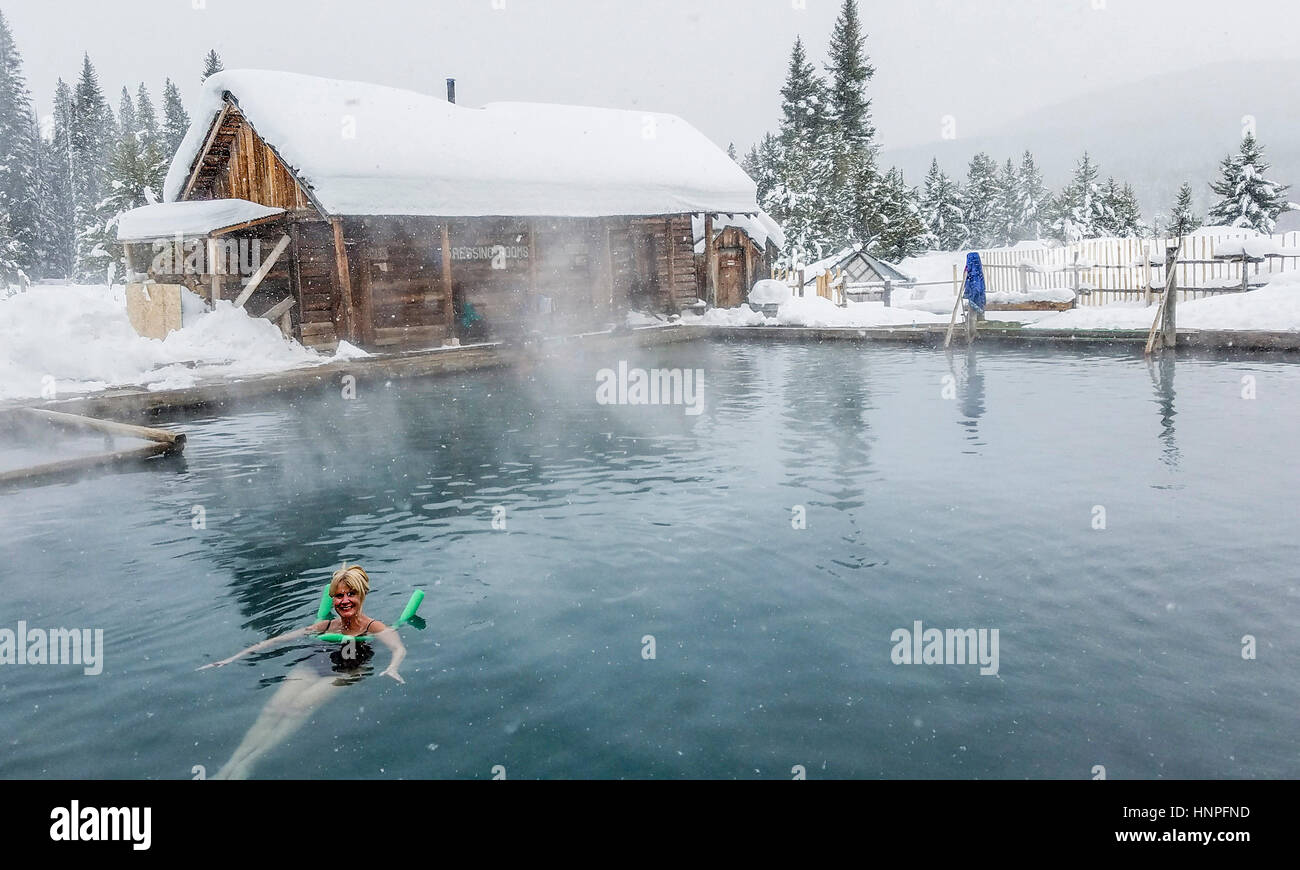 Femme plonge dans l'eau de 100 degrés de la piscine principale à Burgdorf Hot Springs pendant une légère chute de neige. Les ressorts peuvent être atteint en hiver seulement par sno Banque D'Images