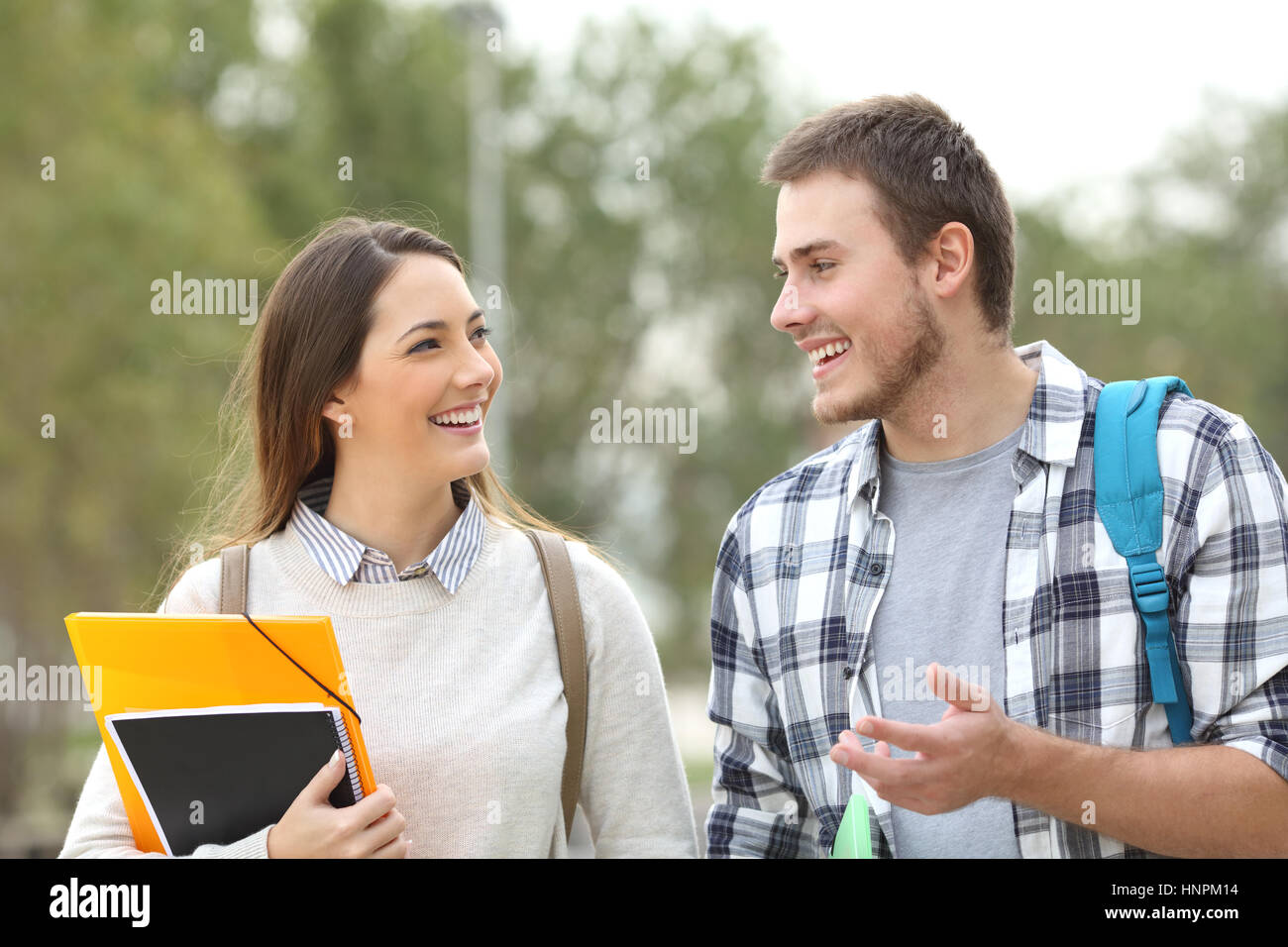 Deux étudiants heureux à marcher en direction de la caméra et de parler dans un parc ou d'un campus universitaire Banque D'Images