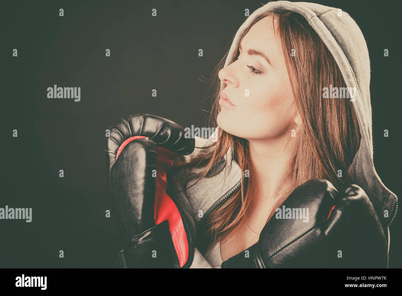 L'exercice de se préparer à se battre. L'esprit sportif et le corps solide. Regarder côté jeune femme porter des vêtements et des gants de boxe. Stand avec des mains croisées ho Banque D'Images