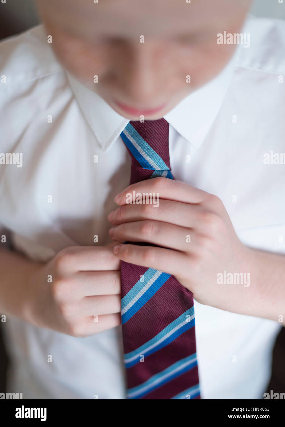 Un garçon bouclant sa cravate de l'uniforme scolaire. Banque D'Images