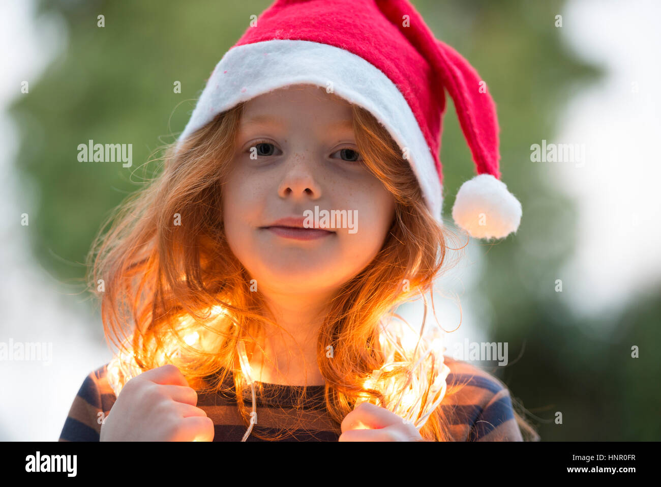 Une petite fille vêtue d'un chapeau de Père Noël et de la féerie de lumières de Noël Banque D'Images