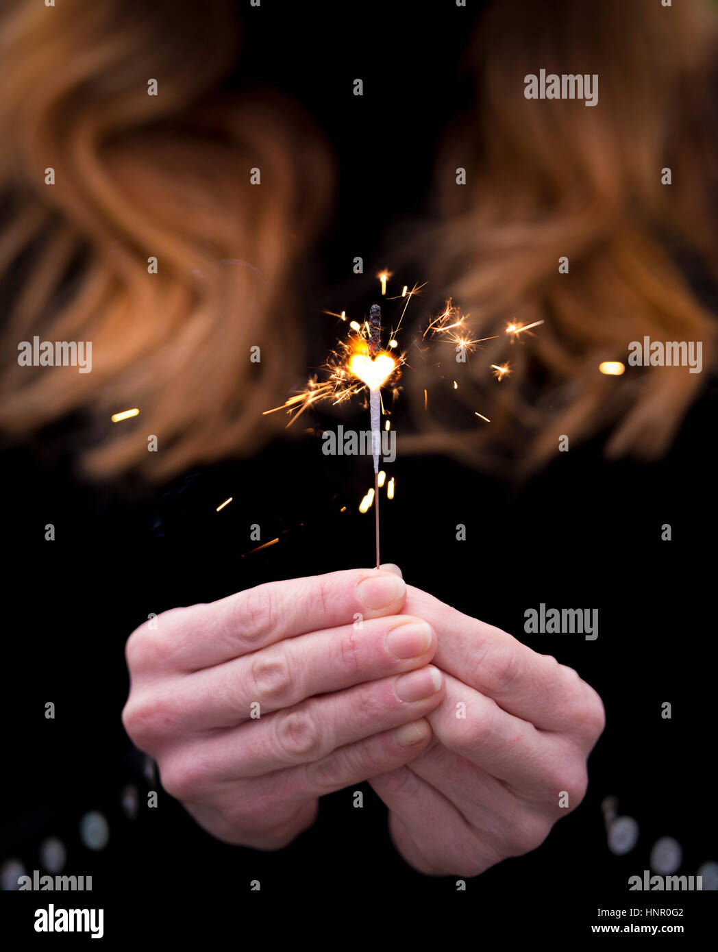 Un red haired woman holding a sparkler. Banque D'Images