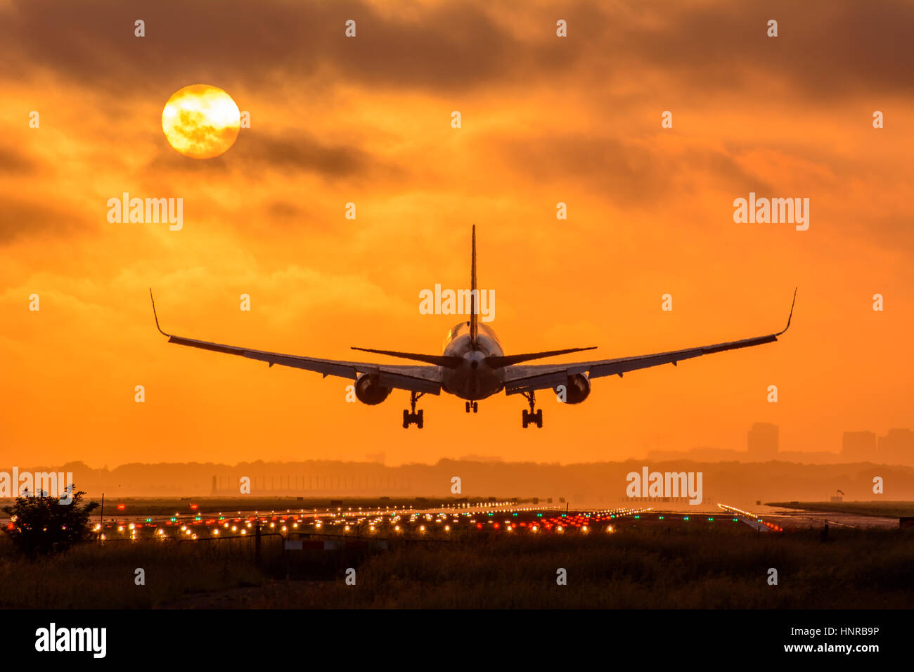 Avion est l'atterrissage pendant le lever du soleil. Photo est prise sur un ciel nuageux le matin tôt. Banque D'Images