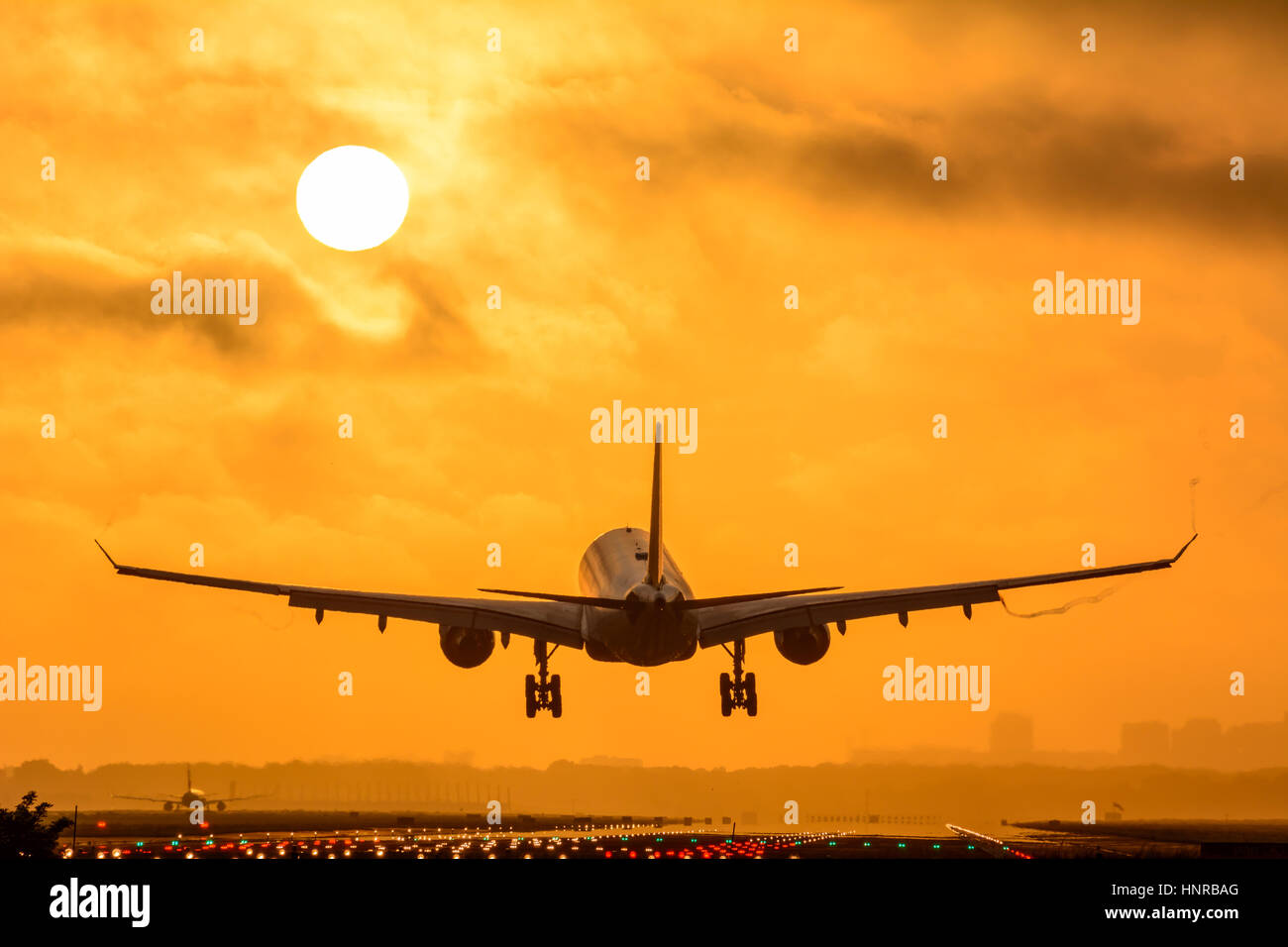 Avion est l'atterrissage pendant le lever du soleil. Photo est prise sur un ciel nuageux le matin tôt. Banque D'Images