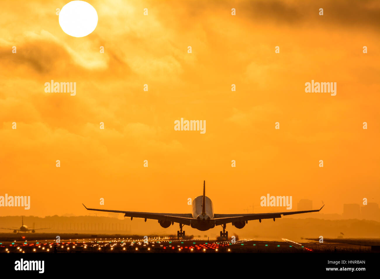 Avion est l'atterrissage pendant le lever du soleil. Photo est prise sur un ciel nuageux le matin tôt. Banque D'Images